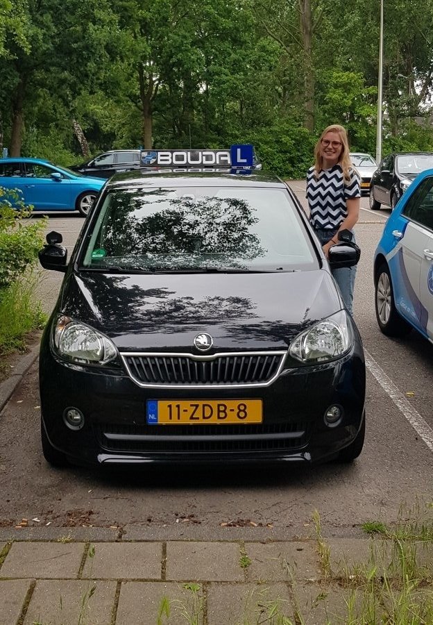 Geslaagde leerling naast een lesauto van Rijschool Bouda